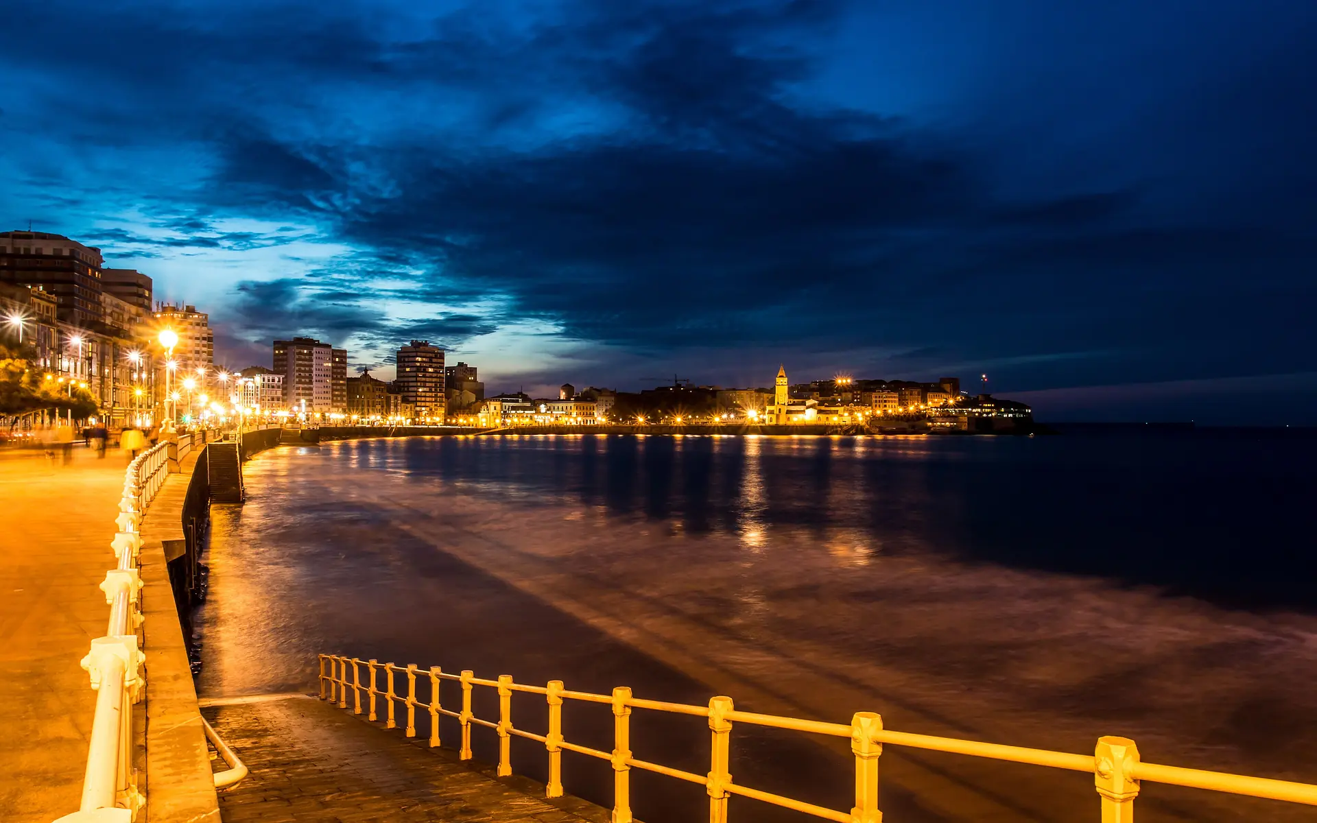 Paseo del Muro y playa de San Lorenzo iluminados al anochecer
